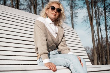 Güz parkında tek başına bankta oturan güzel bir kadın, yaşam tarzı insan konsepti.