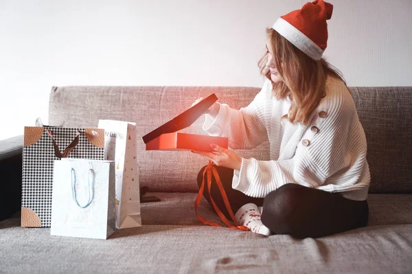 Belleza chica apertura regalo sentado en el sofá en casa —  Fotos de Stock