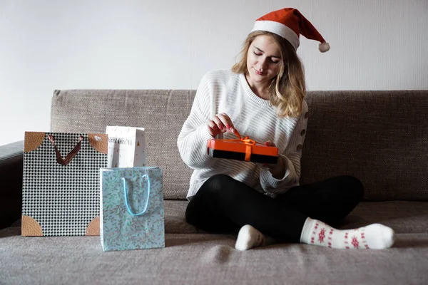 Belleza chica apertura regalo sentado en el sofá en casa —  Fotos de Stock