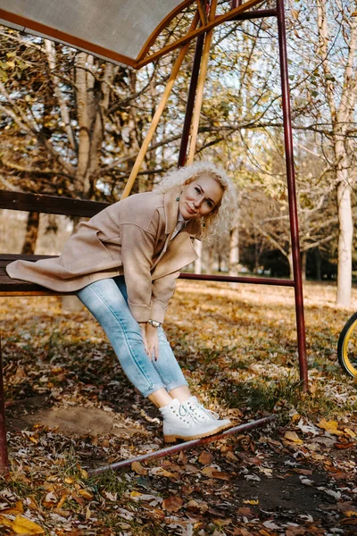 Portret van een glimlachende vrouw van middelbare leeftijd zittend en schommelend op schommel in het park — Stockfoto