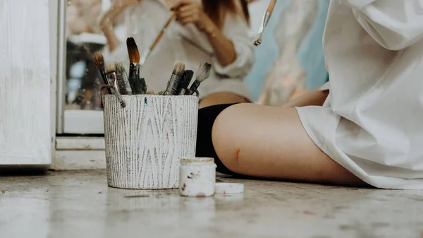 Una pintora sentada en el suelo frente al espejo. Interior del estudio de arte —  Fotos de Stock