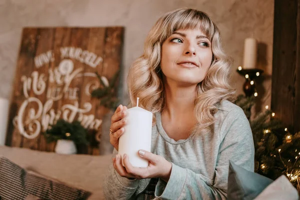 Jovem atraente sorrindo enquanto segura uma vela comemorando o Natal — Fotografia de Stock