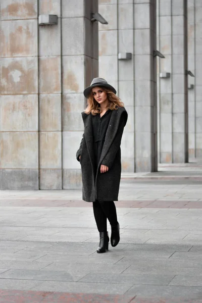 Egy gyönyörű nő portréja, kalapban és szürke kabátban. teljes hossz fotó a városban — Stock Fotó