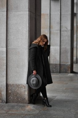 Şapkalı ve gri ceketli güzel bir kadının portresi. Şehirde tam boy fotoğraf