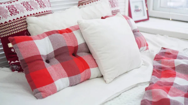 Zimowe dekoracje świąteczne. Czerwone białe poduszki na łóżku — Zdjęcie stockowe