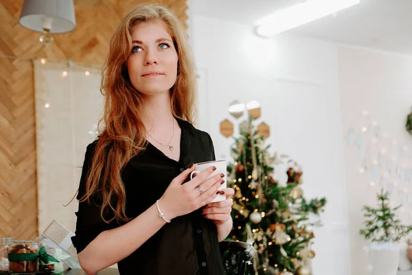 Mujer sostiene una taza de café por la mañana en la cocina de Navidad — Foto de Stock