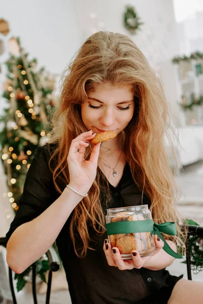 Счастливая молодая женщина ест рождественское печенье на кухне — стоковое фото