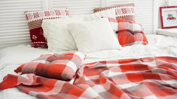 Decoraciones navideñas de invierno. Almohadas blancas rojas en la cama — Foto de Stock