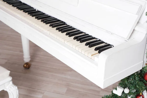 Klucze na białym fortepianie pionowym z dekoracją świąteczną — Zdjęcie stockowe