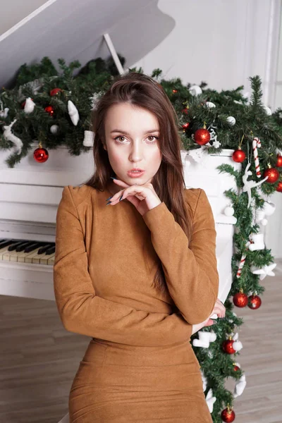 Chica cerca de un piano de cola blanco con decoración navideña — Foto de Stock