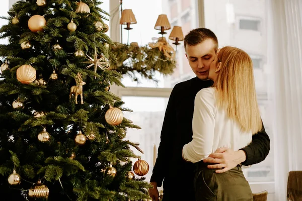 Imagen que muestra a una joven pareja abrazándose sobre un árbol de Navidad —  Fotos de Stock