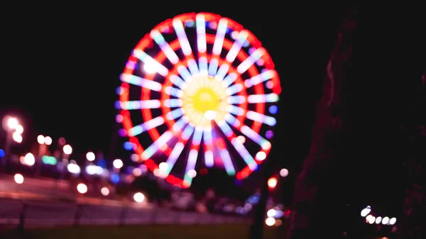Out of focus abstract of ferris wheel and empty road at night — Stock Photo, Image