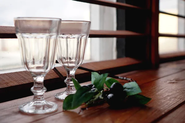 Window with a wooden cozy windowsill empty glasses and flower decor — Stock Photo, Image