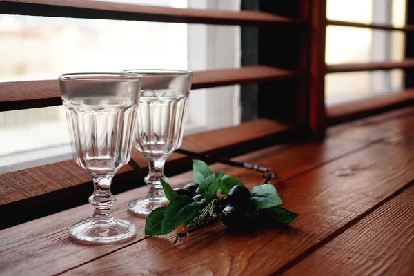 Окно с деревянным уютным подоконником пустые бокалы и цветочный декор — стоковое фото