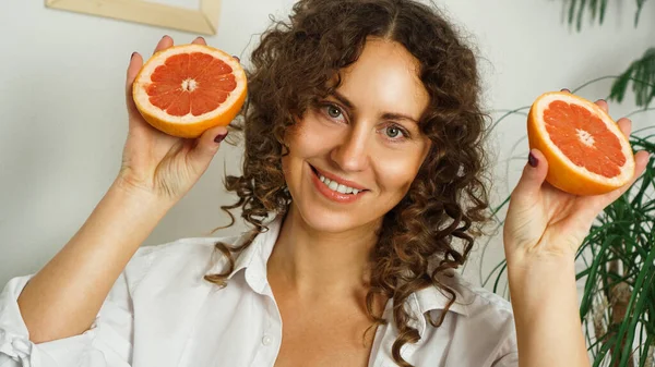Портрет красивой женщины средних лет с вьющимися волосами и грейпфрутом — стоковое фото