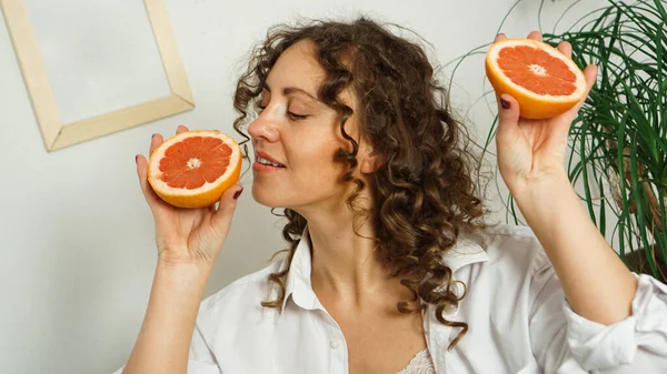 Портрет красивой женщины средних лет с вьющимися волосами и грейпфрутом — стоковое фото