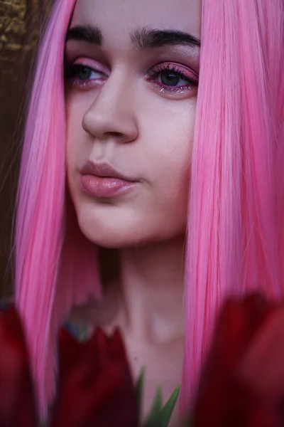 Retrato de uma menina sonhadora com cabelo rosa brilhante com flores perto do rosto — Fotografia de Stock