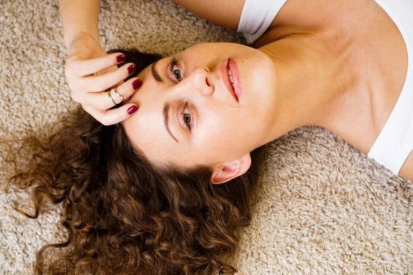 Mujer acostada en la alfombra, feliz chica joven adulta tumbada en el suelo —  Fotos de Stock