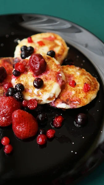 Cheese Pancakes with berries on a black plate. — Stock Photo, Image