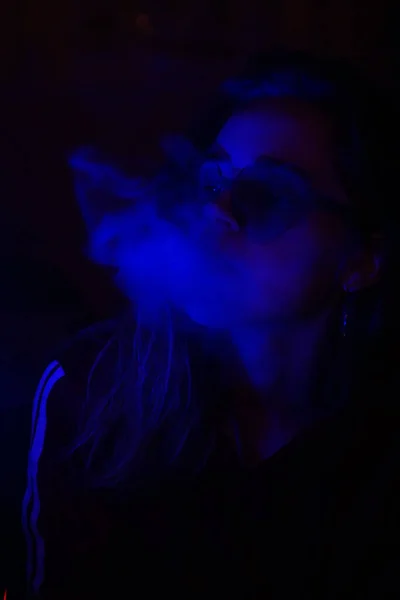 Nahaufnahme Porträt eines dampfenden Mädchens in neonblauem Licht — Stockfoto