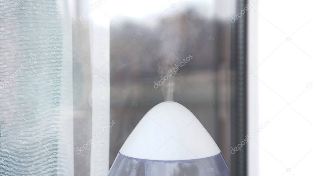 The white ultrasonic humidifier on a window of living room