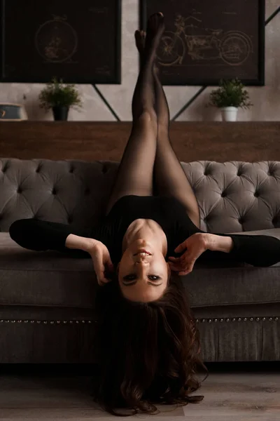 Schöne junge Frau in einer schwarzen transparenten Strumpfhose auf einer Couch — Stockfoto