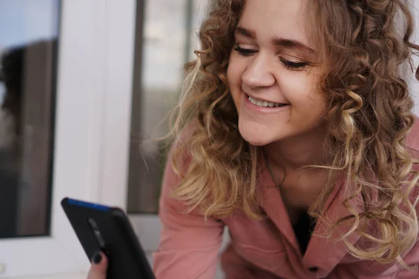 Joven hermosa alegre con pelo rizado con teléfono inteligente — Foto de Stock