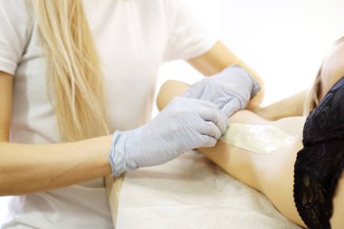 Spatulayla koltukaltını cilalayan kadın. Balmumu güzellik salonu epilasyon prosedürü