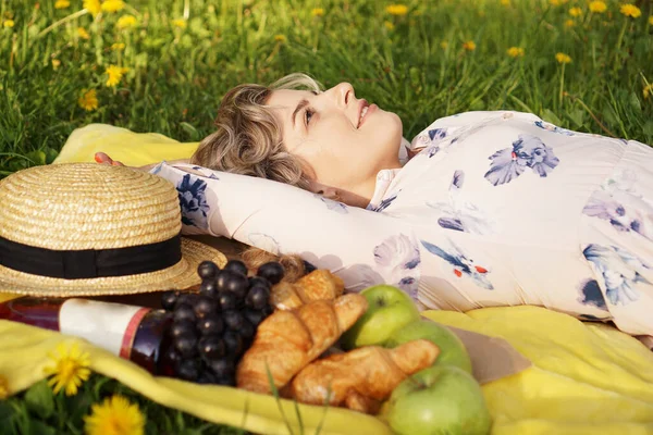 Mladá dívka ležící na kostkovaném plotě. Piknik. Přírodní světlo — Stock fotografie