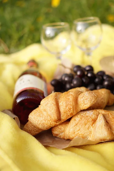 Пікнік на траві з круасаном, рожевим вином, солом'яним капелюхом, виноградом на жовтій плед — стокове фото