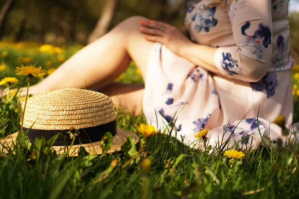 Mulher com um chapéu de palha num campo de flores. Foco no chapéu — Fotografia de Stock