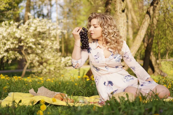 Donna con uva a un picnic nel giardino estivo — Foto Stock