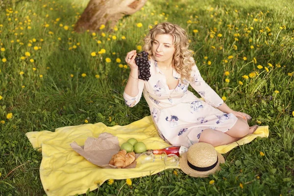 Donna con uva a un picnic nel giardino estivo — Foto Stock