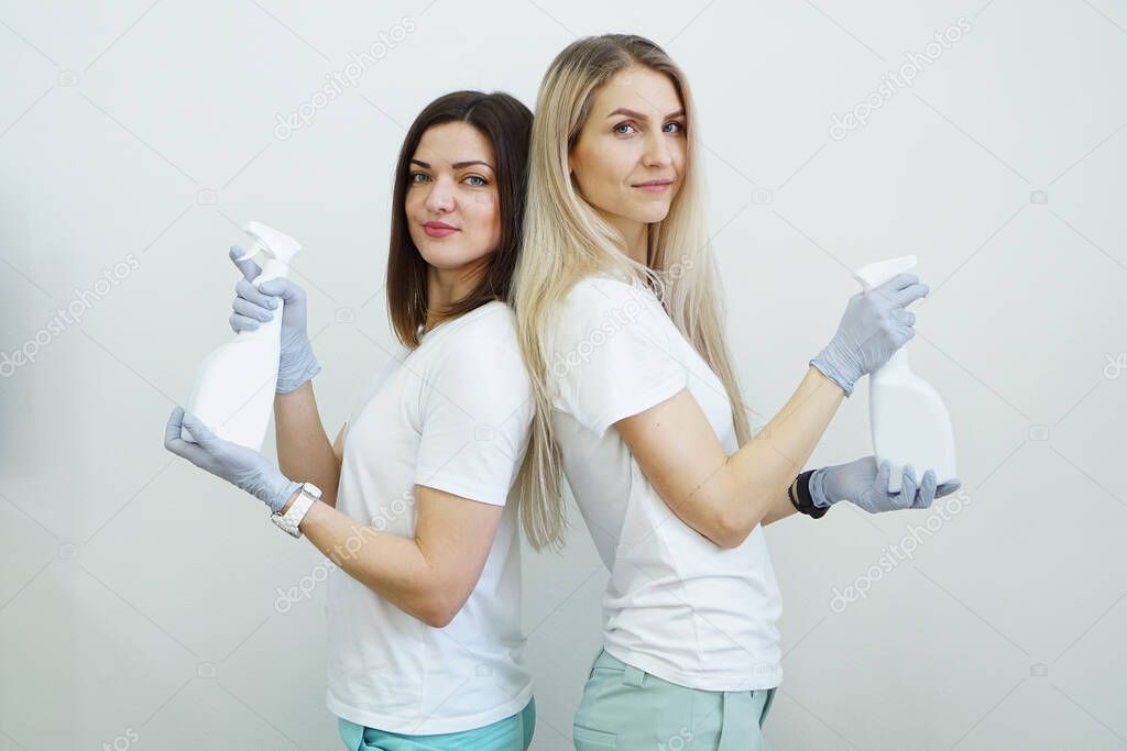 Two women hold spray bottle with antiseptic or detergent like guns. Health concept