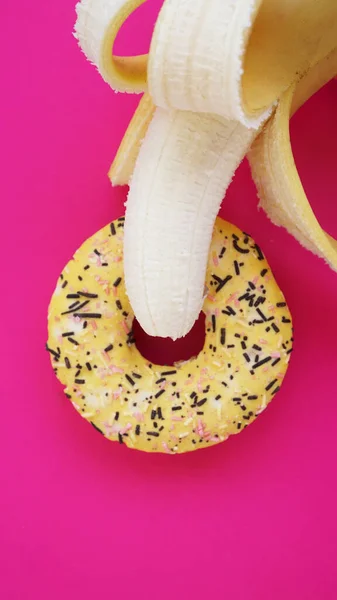 Doce donut e banana no fundo cor-de-rosa. Conceito erótico — Fotografia de Stock