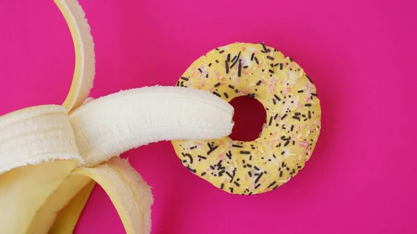 Doce donut e banana no fundo cor-de-rosa. Conceito erótico — Fotografia de Stock