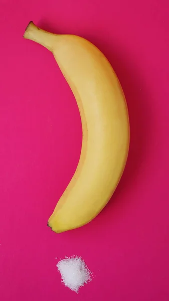 Banana e açúcar em um fundo rosa — Fotografia de Stock