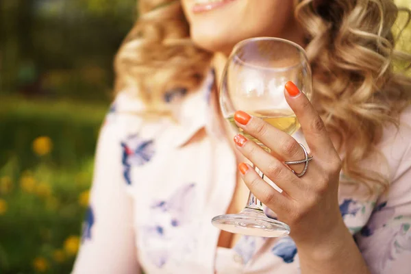 Счастливая блондинка с бокалом белого вина во время пикника на закате в парке — стоковое фото