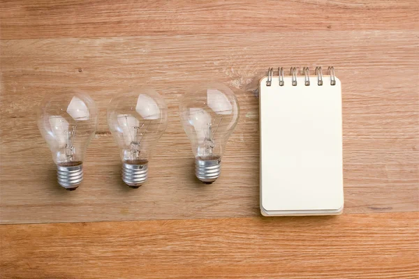 Opened spiral notebook with light bulb — Stock Photo, Image