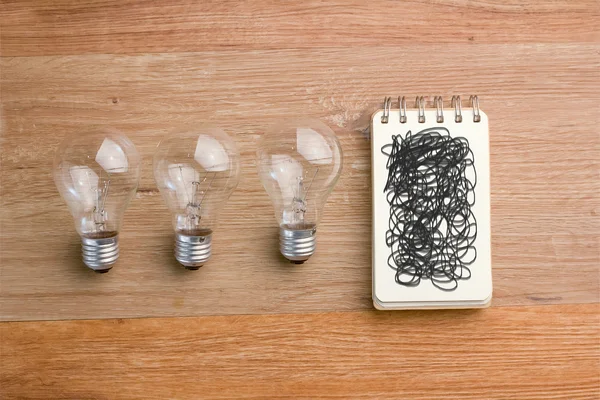 Opened spiral notebook with light bulb — Stock Photo, Image