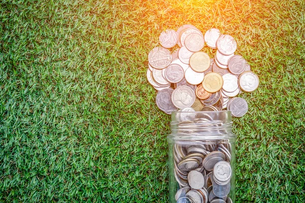 Moedas em dinheiro jar no fundo grama — Fotografia de Stock