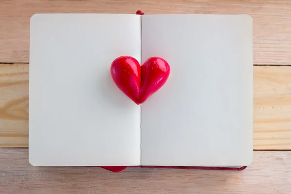 Книга з відкритими сторінками і глиняною формою серця посередині — стокове фото