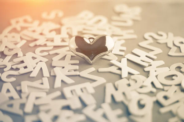 Corazón dorado sobre un fondo de alfabeto de madera . — Foto de Stock