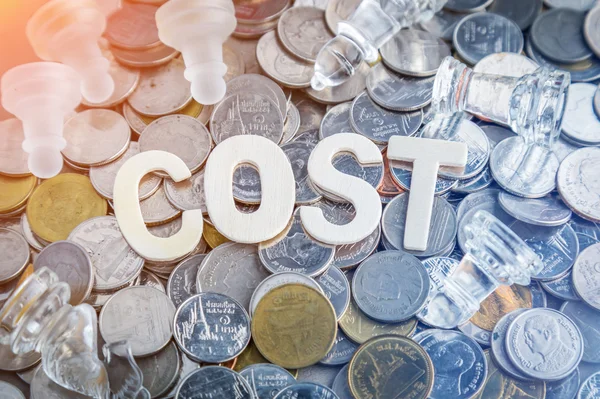 De houten letters close-up van kosten woord met hoop van munten — Stockfoto