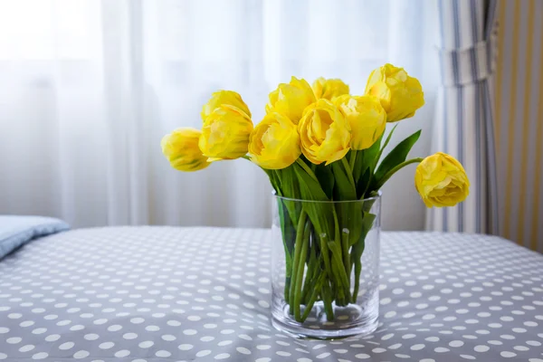 Klarglas vas som innehåller snitt gula tulpaner och klarglas — Stockfoto