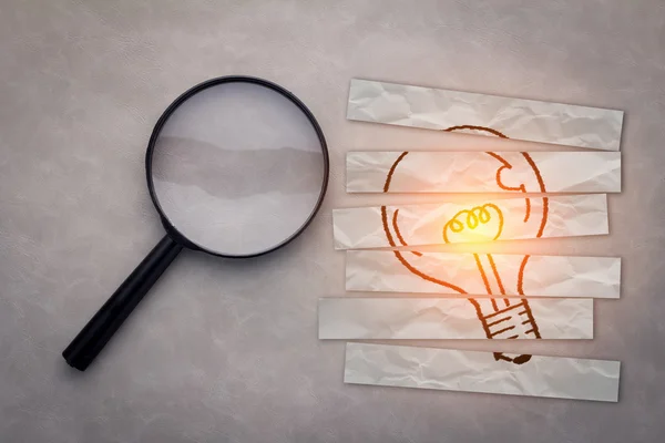 Magnifying glass with drawing light bulb — Stockfoto