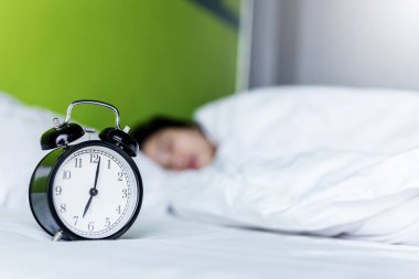 Evdeki yatak odasında uyuyan genç kadın ve çalar saat..