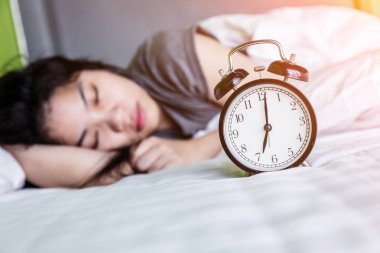 Evdeki yatak odasında uyuyan genç kadın ve çalar saat..