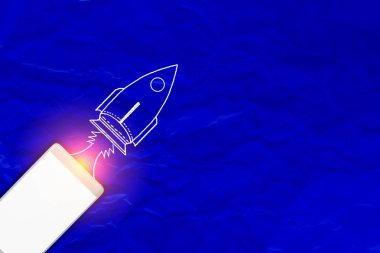 Mavi kağıt arka plan kopya alanı ve roket ile akıllı telefon 
