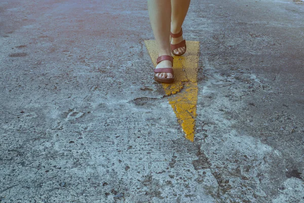 Sinal de rua de direção amarela com passeio de mulher em sapato de couro — Fotografia de Stock